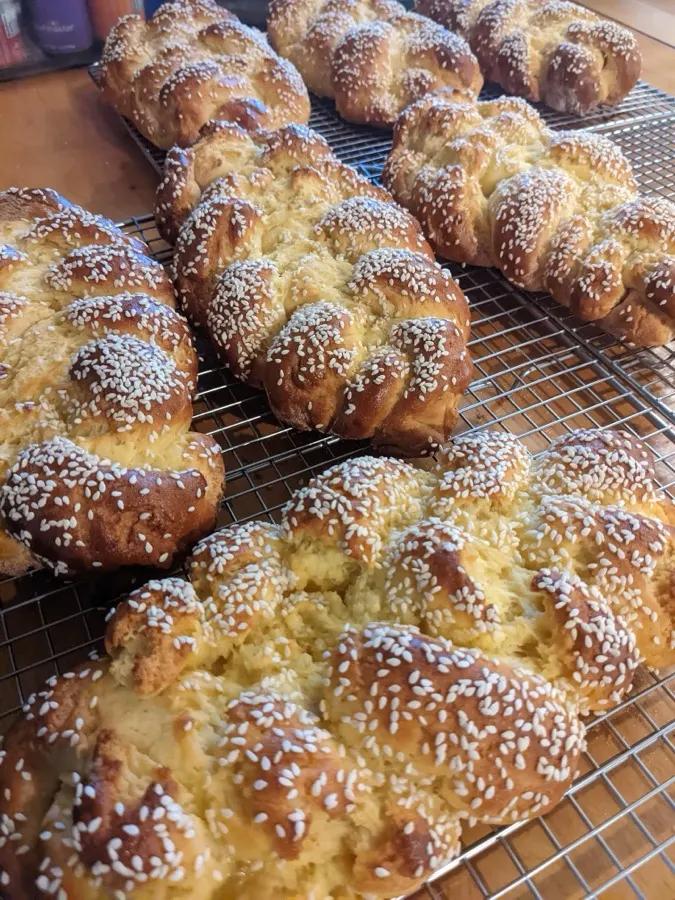 Braided challah loaves with sesame seeds cooling on racks